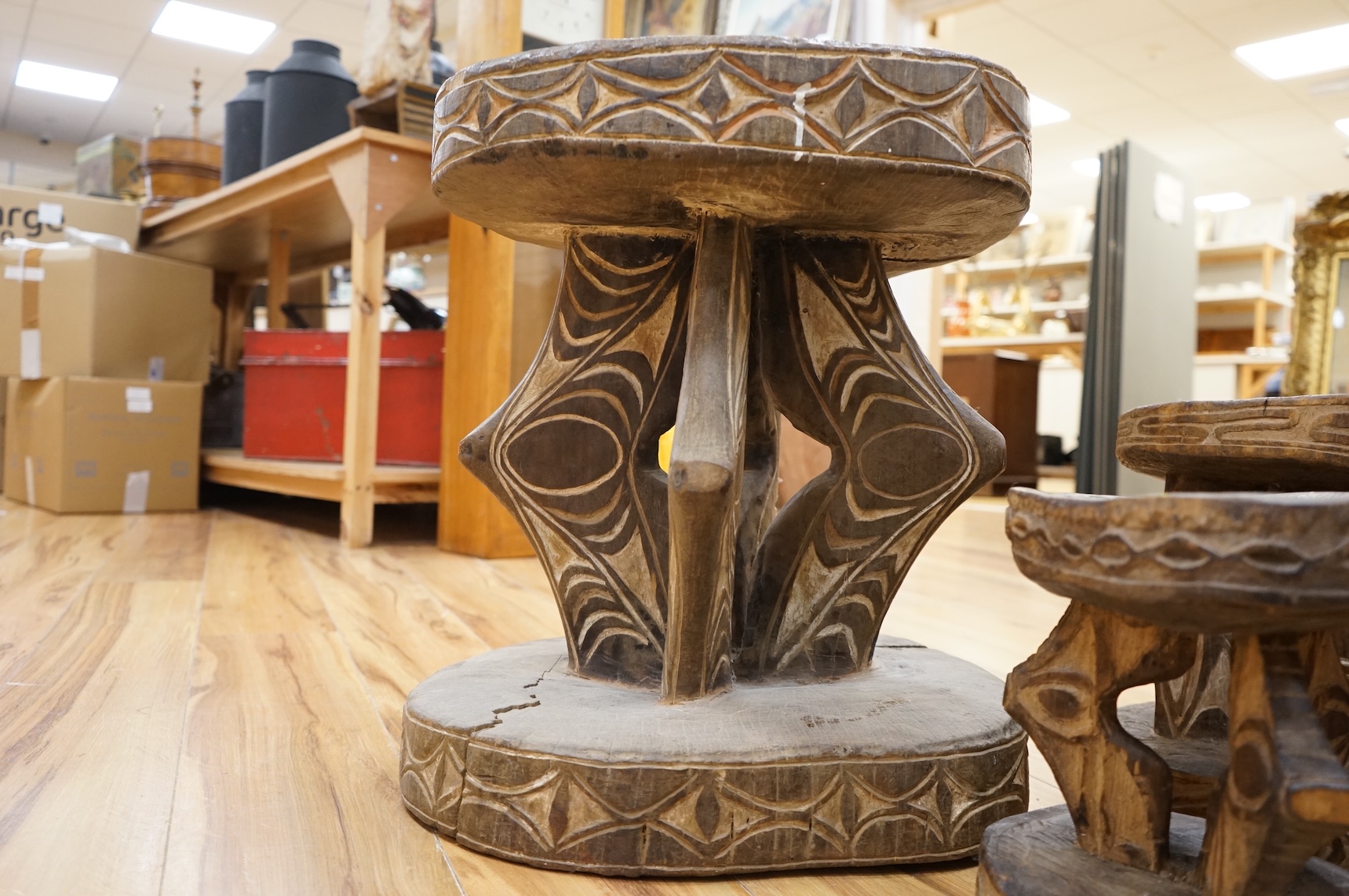 Papua New Guinea Sepik River, two tribal tables, each carved from a section of tree trunk, with circular top and base, the supports and edges incised and painted with geometric designs and two other small stools, largest